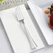 A Visions heavy weight silver plastic fork on a napkin next to a plate of food.