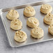 Preformed Otis Spunkmeyer white chocolate macadamia nut cookies on a baking tray.