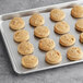 A gray baking tray filled with round Otis Spunkmeyer peanut butter cookies.