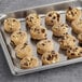 A baking tray filled with Otis Spunkmeyer triple chocolate cookies on a gray surface.