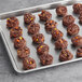 A chocolate cookie with REESE'S PIECES candy on a gray tray.