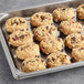 A baking tray filled with Otis Spunkmeyer oatmeal raisin cookies on a gray surface.