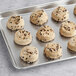 A tray of Otis Spunkmeyer chocolate chip cookies with chocolate chips on a gray surface.