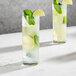 Two Della Luce highball glasses filled with a lime and mint drink garnished with lime slices.