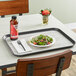 A Dinex woodgrain non-skid tray with a salad and a bottle of water on it.