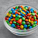 A bowl filled with M&M's Mini Peanut Butter Milk Chocolate Candies on a table.