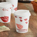 Two EcoChoice paper cups with leaf print on a table with coffee