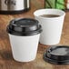 Two white Choice double wall paper cups with black lids on a table.