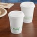 Two EcoChoice white compostable paper cups with lids on a table.