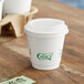A white EcoChoice double wall paper hot cup with a lid on a table.