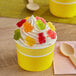 A yellow cupcake with whipped cream and Albanese 5 Natural Flavor Gummi Bears on top.