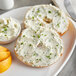 A bagel with Don's Salads Triple Onion Cream Cheese and chives on a plate.