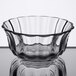 A Libbey clear glass bowl with a wavy edge on a reflective surface.
