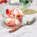 A Libbey glass bowl filled with ice cream, strawberries, and a spoon.