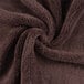 A close up of a brown Monarch Brands coral fleece hand towel with a spiral pattern.