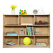 A Flash Furniture wood classroom storage cabinet with books and toys on top.
