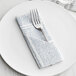 A blue and white Hoffmaster FashnPoint dinner napkin with a fork on a plate.