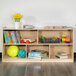A Flash Furniture wood classroom storage cabinet with books and toys on the shelves.