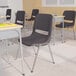 A Flash Furniture Hercules gray shell stack chair with chrome legs in a classroom with desks and chairs.