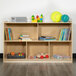 A Flash Furniture wood classroom storage cabinet with books and toys on top.