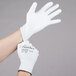 A person's hands wearing small white Cordova Halo gloves with white polyurethane palms.