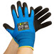 A pair of hands wearing blue and black Cordova iON gloves with a black nitrile palm coating.