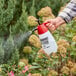 A hand using a Chapin Farm and Field Handheld Sprayer to spray plants.