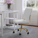 A Martha Stewart white faux leather armless office chair with a polished brass base.