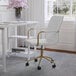 A Martha Stewart white faux leather office chair with a polished brass finish.