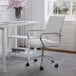 A Martha Stewart white faux leather swivel office chair with a polished nickel base in front of a white desk.