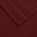 A close up of a burgundy Intedge poly/cotton blend table cover.