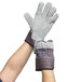 A pair of hands wearing Cordova striped canvas work gloves with leather palms and rubber cuffs.