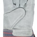 A Cordova warehouse work glove with red and blue stripes on the cuff and gray leather palm.