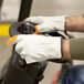 A person wearing Cordova leather driver's gloves with hi-vis orange fingertips.