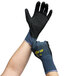 A pair of hands wearing Cordova ActivGrip Advance warehouse gloves with purple and gray fabric and black nitrile palms.