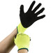 A pair of hands wearing hi-vis green gloves with black foam latex palms.