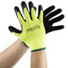 A pair of hands wearing Cordova small green polyester/cotton work gloves with black foam latex palm coating.