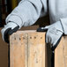 A person wearing Cordova gray nylon gloves with black foam nitrile palm coating holds a piece of wood.