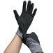 A pair of small Cordova Conquest Xtra gray and black gloves with foam nitrile and polyurethane coating being put on