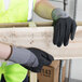 A person wearing Cordova Conquest Xtra safety gloves holding a piece of wood.