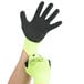 A pair of yellow nylon gloves with black foam latex coating and green tips.