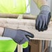 A person wearing Cordova Conquest Plus safety gloves and holding a piece of wood.