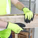 A person wearing Cordova Cold Snap safety gloves with black foam latex palm coating holding a piece of wood.