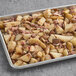 A baking pan filled with potatoes, apples, and bacon.