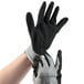 A pair of hands wearing black and gray Cordova Cor-Touch foam nitrile gloves.