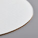 A close up of a Baker's Mark white corrugated cake circle.