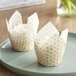 Two Baker's Mark tulip cupcake wrappers with a white background and gold flower pattern.