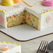 A cake with a slice missing on a white quarter sheet cake pad.