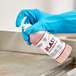 A hand in a blue glove holding a bottle of Noble Chemical Blast ready-to-use liquid cleaner.