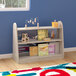A Flash Furniture wooden double-sided shelf with clear plastic dividers holding books and toys.